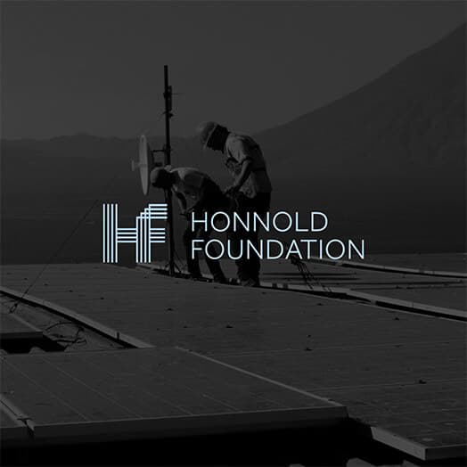 The Honnold Foundation logo set over a photograph of a solar array against a mountain ridge.